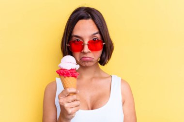 Sarı arka planda izole edilmiş dondurma tutan melez bir kadın.