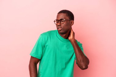 Genç Afro-Amerikan erkek, pembe arka planda izole edilmiş, sabit yaşam tarzından dolayı boyun ağrısı çekiyor..