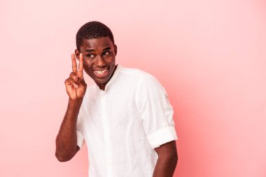 Genç Afrikalı Amerikalı adam pembe arka planda izole edilmiş. İki numarayı parmaklarıyla gösteriyor..