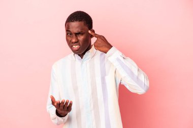 Genç Afrikalı Amerikalı bir adam pembe arka planda izole edilmiş ve elinde bir ürün tutuyor..