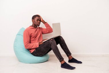 Beyaz arka planda izole edilmiş bir dizüstü bilgisayar kullanan genç Afrikalı Amerikalı adam şok olurken, önemli bir buluşmayı hatırladı..