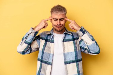 Sarı arka planda izole edilmiş genç beyaz adam bir göreve odaklanmış, işaret parmaklarını işaret ediyor..