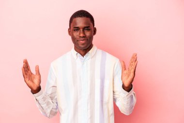 Genç Afrikalı Amerikalı bir adam pembe arka planda izole edilmiş. Elinde parmakları olan, gülümseyen ve kendinden emin bir şey var..