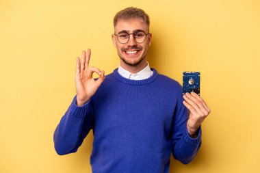 Young computer man isolated on yellow background cheerful and confident showing ok gesture.