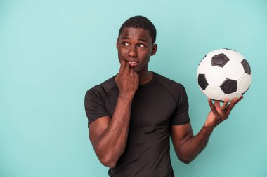 Mavi arka planda izole bir şekilde futbol oynayan genç Afrikalı Amerikalı bir adam bir şeyin fotokopi alanına baktığını düşünerek rahatladı..