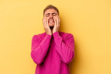 Kafkasyalı genç adam sarı arka planda izole edilmiş sızlanıyor ve ağlıyordu..
