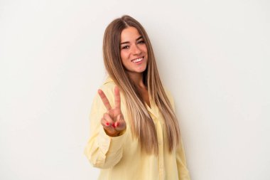 Beyaz arka planda izole edilmiş genç bir Rus kadın zafer işareti gösteriyor ve gülümsüyor..