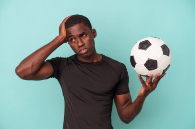 Mavi arka planda izole bir şekilde futbol oynayan genç Afrikalı Amerikalı adam şok olmuştu..