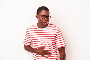 Beyaz arka planda izole edilmiş genç Afrikalı Amerikalı adam karnına dokunuyor, nazikçe gülümsüyor, yemek yiyor ve tatmin oluyor..