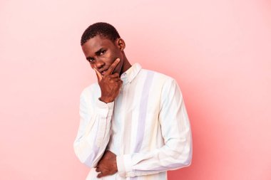 Genç Afro-Amerikalı bir adam pembe arka planda izole edilmiş, bir strateji planlıyor, bir iş hayatının nasıl olacağını düşünüyor..