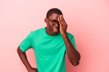 Genç Afrikalı Amerikalı bir adam pembe arka planda izole edilmiş. Yüzünün yarısını palmiye ile örterek eğleniyor..