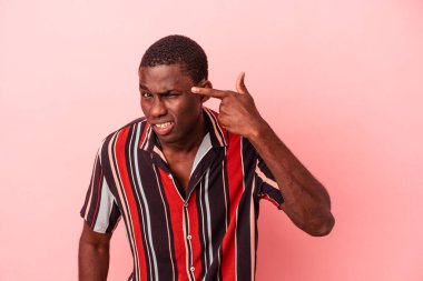 Pembe arka planda izole edilmiş genç Afro-Amerikalı adam işaret parmağıyla hayal kırıklığı jesti yapıyor..