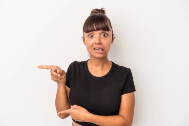 Beyaz arka planda izole edilmiş genç melez kadın işaret parmağıyla fotokopi alanını işaret ederek şok oldu..