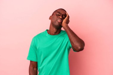 Pembe arka planda izole edilmiş genç Afrikalı Amerikalı adam yorgun ve uykulu..