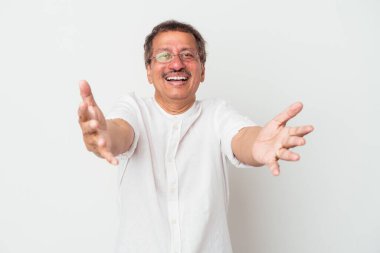 Middle aged indian man isolated on white background feels confident giving a hug to the camera.