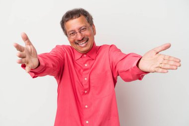 Middle aged indian man isolated on white background feels confident giving a hug to the camera.