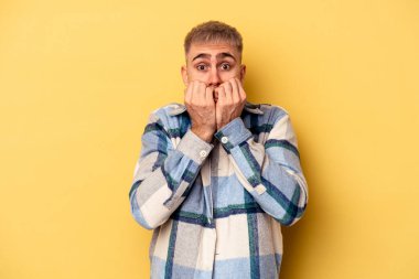 Sarı arka planda izole edilmiş, tırnak yiyen, gergin ve endişeli genç bir beyaz adam..