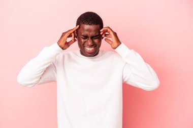 Genç Afrikalı Amerikalı adam pembe arka planda izole edilmiş kulakları elleriyle kapatıyor..