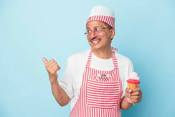 Senior american ice cream man holding an ice cream isolated on blue background points with thumb finger away, laughing and carefree.