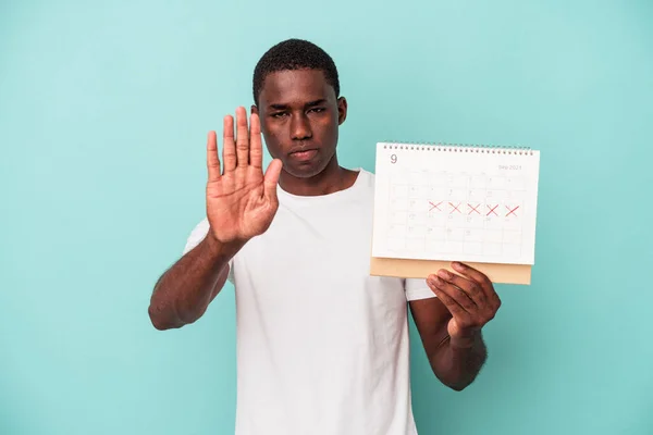 Jonge Afro Amerikaanse Man Houdt Een Kalender Geïsoleerd Blauwe Achtergrond — Stockfoto