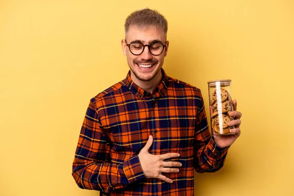 Young Caucasian Man Holding Cookies Jar Isolated Yellow Background Laughing — Photo