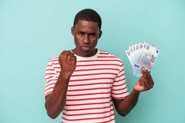Молодой Афроамериканец Держит Банкноты Синем Фоне Показывая Кулак Камере Агрессивное — стоковое фото