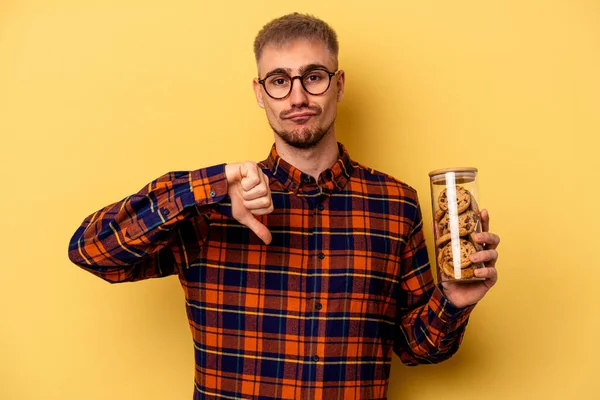 Young Caucasian Man Holding Cookies Jar Isolated Yellow Background Showing — Stock fotografie