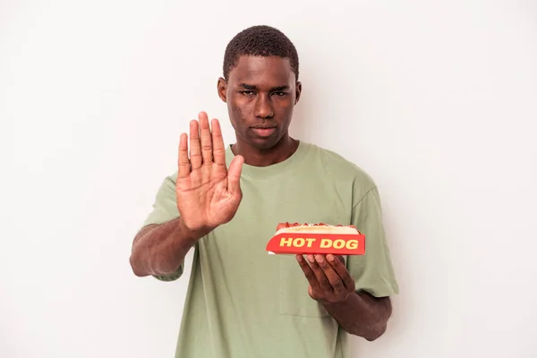 Młody Afroamerykanin Jedzący Hot Doga Białym Tle Stojący Wyciągniętą Ręką — Zdjęcie stockowe