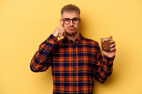 Young Caucasian Man Holding Almond Jar Isolated Yellow Background Showing — Zdjęcie stockowe