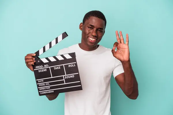 Jonge Afro Amerikaanse Man Houdt Clapperboard Geïsoleerd Blauwe Achtergrond Vrolijk — Stockfoto