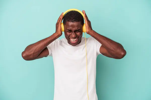 若いアフリカ系アメリカ人男性の音楽に耳を傾けます青の背景に隔離された手で耳をカバー — ストック写真