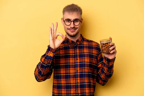 Young Caucasian Man Holding Almond Jar Isolated Yellow Background Cheerful — Zdjęcie stockowe
