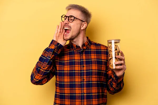 Young Caucasian Man Holding Cookies Jar Isolated Yellow Background Shouting — Stock fotografie