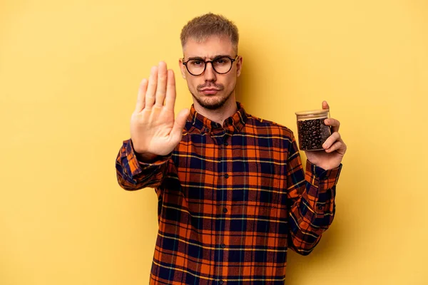 Young Caucasian Man Holding Coffee Jar Isolated Yellow Background Standing — Zdjęcie stockowe