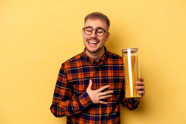 Young Caucasian Man Holding Spaghettis Jar Isolated Yellow Background Laughing — Stock fotografie