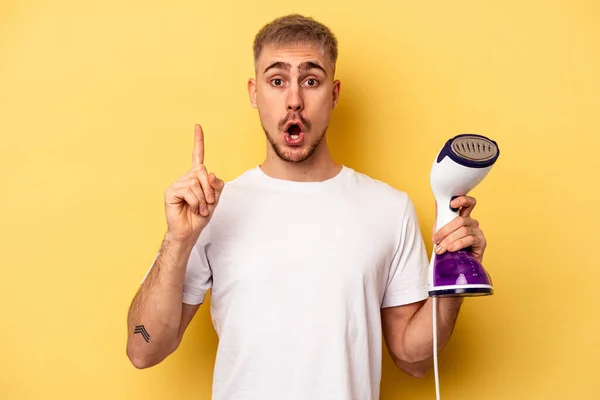 Young Caucasian Man Holding Iron Isolated Yellow Background Having Idea — Stock Photo, Image