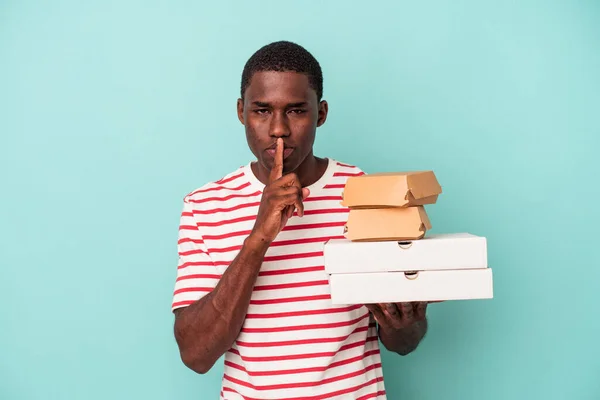 Молодой Афроамериканец Держащий Пиццу Бургеры Голубом Фоне Хранит Секрет Просит — стоковое фото