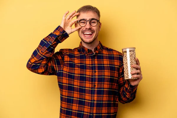 Young Caucasian Man Holding Chickpeas Isolated Yellow Background Excited Keeping — Photo
