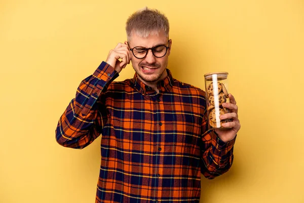 Young Caucasian Man Holding Cookies Jar Isolated Yellow Background Covering — Stockfoto