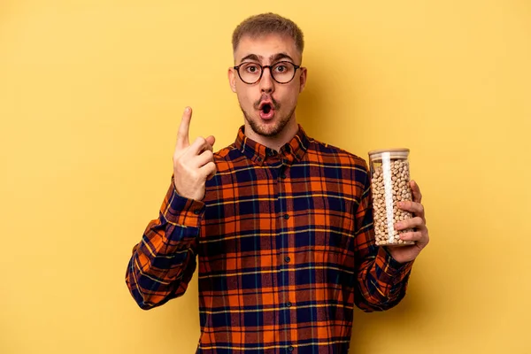 Young Caucasian Man Holding Chickpeas Isolated Yellow Background Having Idea — Stockfoto