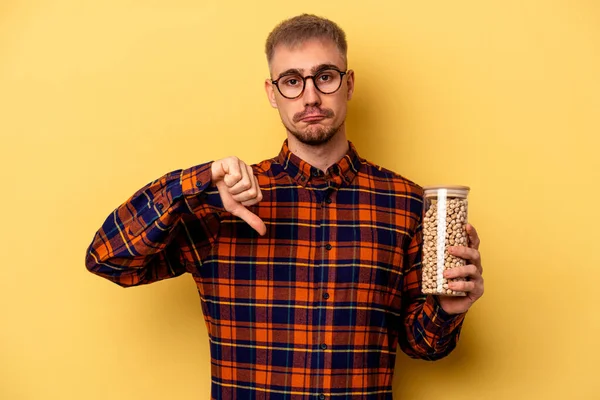 Young Caucasian Man Holding Chickpeas Isolated Yellow Background Showing Dislike — Stock fotografie