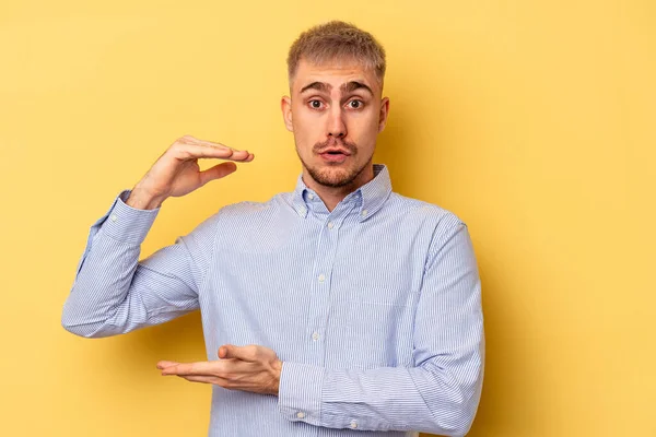 Homem Caucasiano Jovem Isolado Fundo Amarelo Segurando Algo Com Ambas — Fotografia de Stock