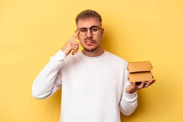 Young Caucasian Man Holding Burger Isolated Yellow Background Showing Disappointment — Stockfoto