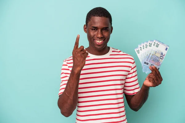 Joven Afroamericano Sosteniendo Billetes Aislados Sobre Fondo Azul Mostrando Número —  Fotos de Stock