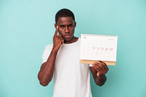 Mladý Afroameričan Drží Kalendář Izolovaný Modrém Pozadí Ukazující Prstem Chrám — Stock fotografie