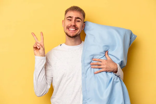 Young Caucasian Man Wearing Pajama Holding Pillow Isolated Yellow Background — ストック写真