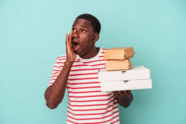 Mladý Afroameričan Drží Pizzy Hamburgery Izolované Modrém Pozadí Křičí Drží — Stock fotografie