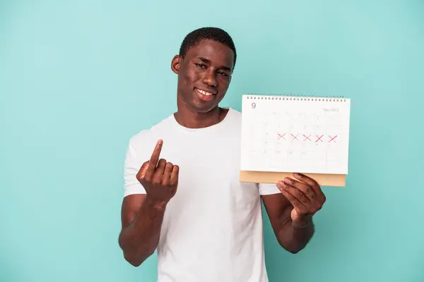 Mladý Afroameričan Drží Kalendář Izolovaný Modrém Pozadí Ukazující Prstem Vás — Stock fotografie