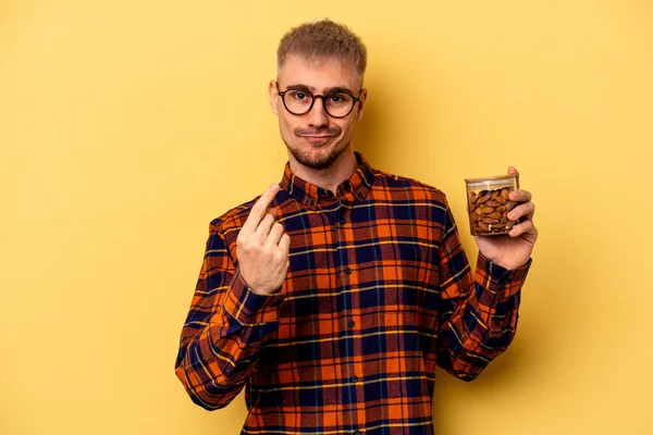 Young Caucasian Man Holding Almond Jar Isolated Yellow Background Pointing — Zdjęcie stockowe