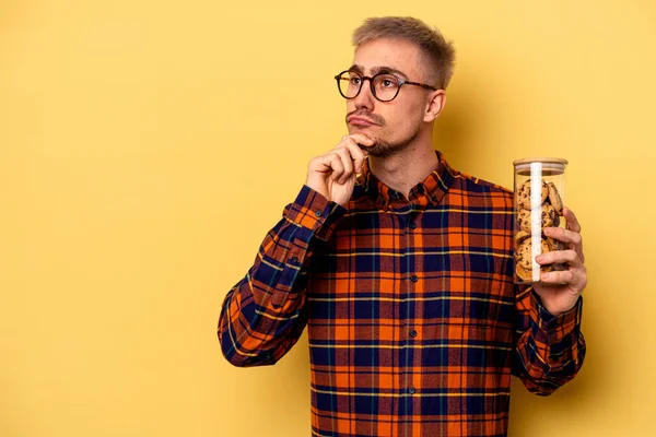 Young Caucasian Man Holding Cookies Jar Isolated Yellow Background Looking — Foto Stock